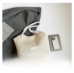 Close-up of beige woven straw tote bag with braided rope handles and fashion label