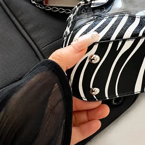 Dettaglio macro della borsa zebrata con cuciture precise e borchie metalliche laterali