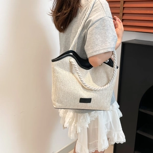 Detail of V-shaped straw weave pattern and thick rope shoulder strap on beige tote bag