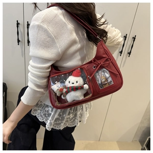 Λεπτομέρεια κόκκινης ita bag με διαφανή παράθυρα, λούτρινο αρκουδάκι και σχέδιο φιόγκου