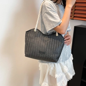 Detail of black straw tote bag with braided white cotton rope handle and logo patch
