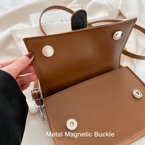 Detailed close-up of the metal magnetic buckle on the brown quilted crossbody bag
