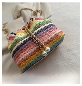 Detail of colorful woven straw bag with golden chain strap and white pearl pendants