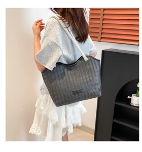 Detail of dark gray straw tote with herringbone pattern and white rope handles