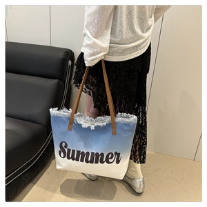 Detail der blau verlaufenden Canvas-Tasche mit Summer-Aufdruck, Fransen und braunen Griffen