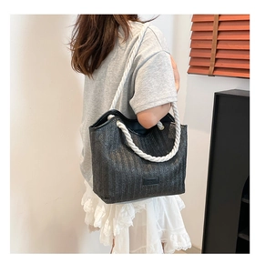 Detail of the black woven texture and thick white cotton rope handles on the tote bag