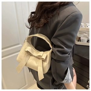 Dettaglio di una mini borsa bianco crema con grande fiocco e tracolla a catena fine