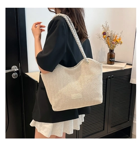 Detail of chevron woven straw tote with thick cotton rope handles and fashion leather patch