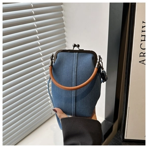 Handheld dark blue denim kiss-lock bag with brown handle and adjustable strap