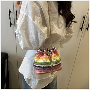 Detalle del bolso tipo cubo de paja tejida arcoíris con cadena metálica dorada de verano