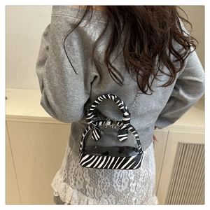 Detail der transparenten PVC-Handtasche mit Zebra-Print und Metallkette am Modell gezeigt