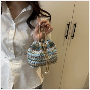 Detalle del bolso saco tejido con motivo de ondas azul y amarillo y cordón de perlas