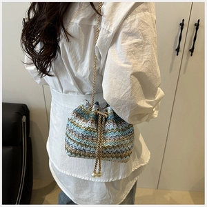 Detalle de bolso saco tejido con bloques de color, cadena dorada y perlas blancas