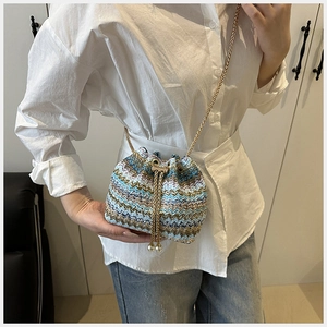 Detalle de bolso tipo saco tejido a mano con diseño de ondas y cadena dorada