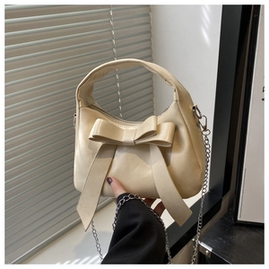 Dettaglio di una borsa beige con fiocco in pelle PU e tracolla a catena in metallo argento
