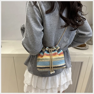 Bolso tipo cubo tejido arcoíris con cordón de perlas y correa de cadena en un modelo