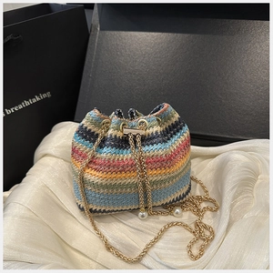 Detail of colorful woven bucket bag with gold chain strap and pearl drawstring accents