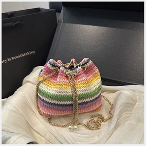 Detail of colorful woven bucket bag with gold chain drawstring and pearl accents