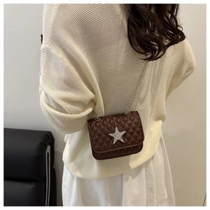 Sac bandoulière marron matelassé avec étoile en strass et chaîne argentée porté par modèle