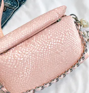 Dettaglio della borsa rosa a tracolla effetto serpente con catena e perle bianche
