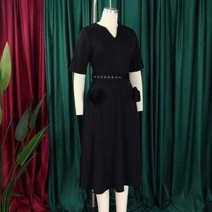 Close-up of elegant black V-neck dress with metal eyelet belt and 3D floral accent