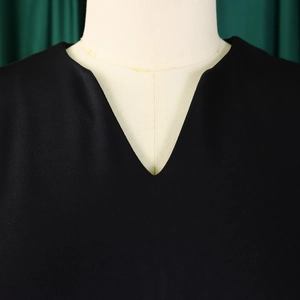Close-up of elegant V-neckline on a black short sleeve A-line dress with refined stitching