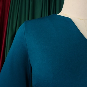 Close-up of deep teal V-neck dress featuring premium horizontal textured fabric details