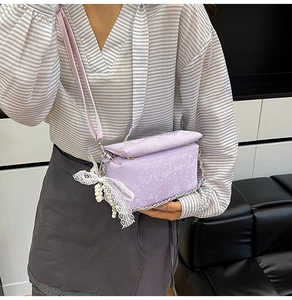 Dettaglio borsa mini viola con trama a serpente e fiocco in pizzo con perla