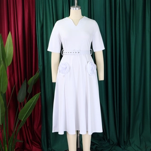 Detail of white V-neck dress featuring 3D floral accents and elegant belted waistline