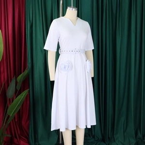 Detail of the white V-neck dress featuring 3D rose flower accents and matching waist belt