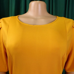 Detail of elegant yellow round neck dress with puffed sleeves and ribbed knit texture