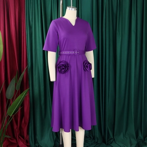 Detail of V-neck short-sleeved purple dress featuring 3D rose floral accents and waist belt