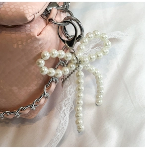 Dettaglio di un ciondolo a fiocco di perle con pizzo bianco e chiusura in metallo argento