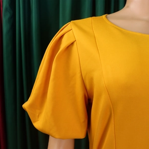 Detailed view of ginger yellow puff sleeves and round neckline on a summer dress