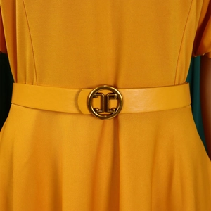 Close-up of a bright yellow A-line dress with an elegant gold buckle belt and woven texture