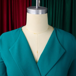 Detail view of the deep teal blazer featuring a classic wide lapel and smooth woven fabric