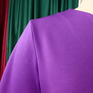 Detailed view of the shoulder seam and textured purple fabric of a women's V-neck dress