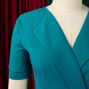 Close-up of elegant V-neckline and short sleeve detail on teal pleated maxi dress