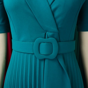 Close-up of pleated peacock green dress with matching belt and v-neckline detail