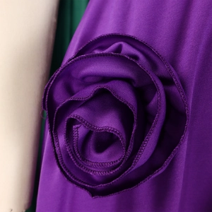 Detail of a large 3D floral decoration on the shoulder of a purple V-neck dress