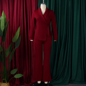 Detail van bordeauxrood tweedelig damespak met overslagblazer, zijstrik en rechte broek