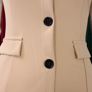 Detail of beige pencil dress showing two black buttons and symmetrical flap pockets