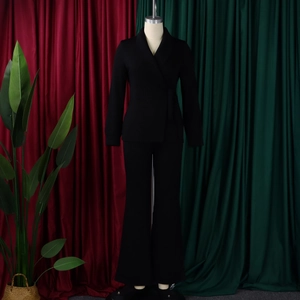 Detail van een elegant zwart damespak met getailleerde blazer en wijde broekspijpen