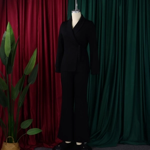 Detail van een zwart damespak met sjaalkraag blazer en uitlopende broek