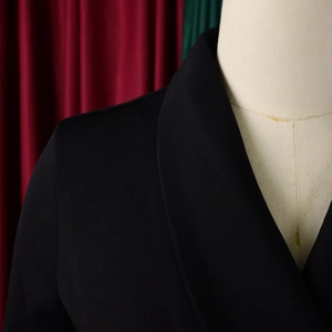Detail van de reverskraag en schoudernaad van een zwarte getailleerde blazer met textuur