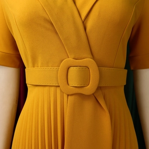 Detailed macro shot of mustard yellow pleated dress with V-neckline and matching belt