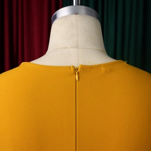 Detail of ginger yellow dress with textured fabric and hidden back zipper on mannequin