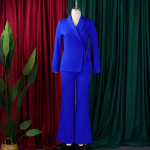 Detail van een koningsblauwe blazer met sjaalkraag, zijstrik en uitlopende broek op een mannequin
