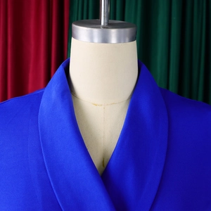 Detail van een koningsblauwe blazer met sjaalkraag en getextureerde gebreide stof