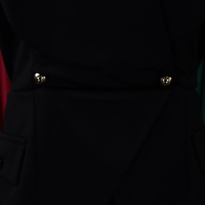 Detailed view of elegant black dress featuring waist pleats and gold polished buttons